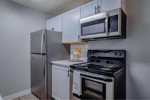 A kitchen with a stainless steel refrigerator, microwave, and oven.