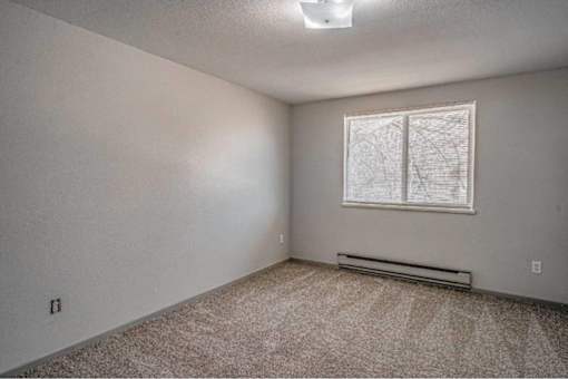 A room with a window and a carpeted floor.