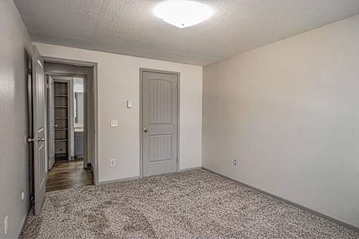 A room with a carpeted floor and a door on the right.