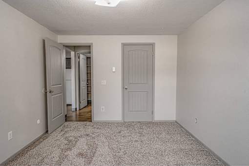 A room with a carpeted floor and two doors.