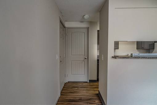 A white door is in a hallway with wood floors.