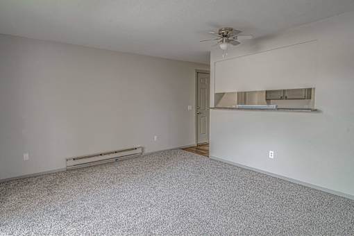 Empty room with a ceiling fan and a radiator on the wall.