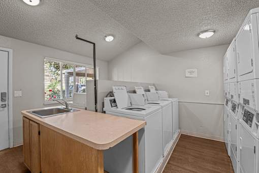 A laundry room with a counter and washers and dryers.