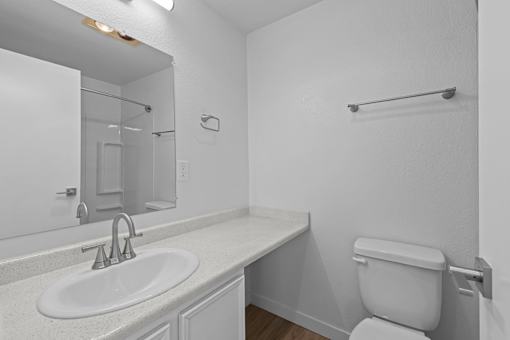 A white bathroom with a toilet, sink, and mirror.