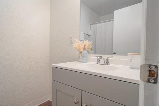 A white bathroom sink with a vase of flowers on top.