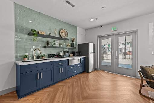 A kitchen with a blue cabinetry and a glass wall.