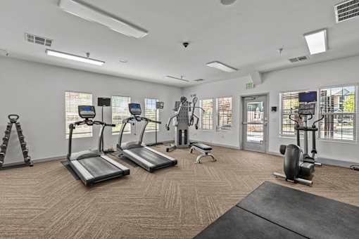 A gym with treadmills, elliptical machines, and a bench.