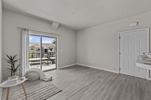 A room with a white door, a table with a plant, and a window with a view of a building outside.