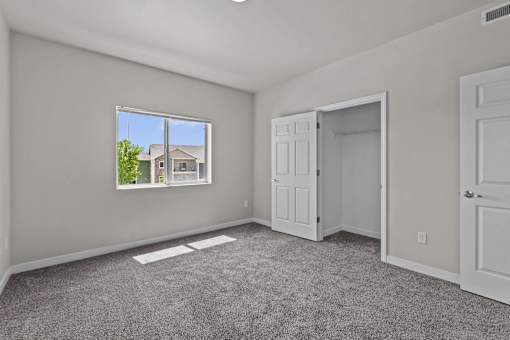 A room with a large window and a view of a house outside.