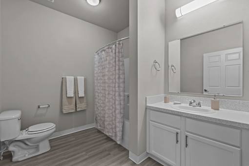 A white bathroom with a toilet, sink, and shower.