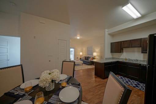 A dining room with a table set for two with candles and flowers.