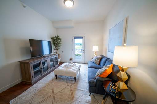A living room with a television, a couch, and a rug.