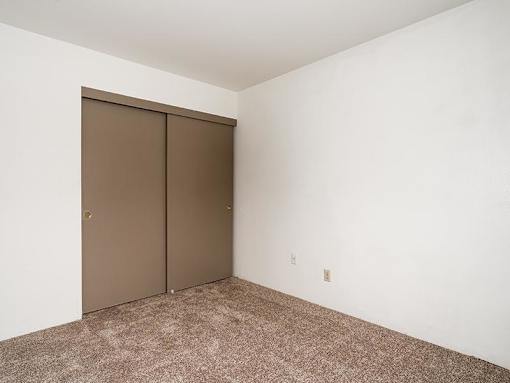 A room with a brown door and carpeted floor.