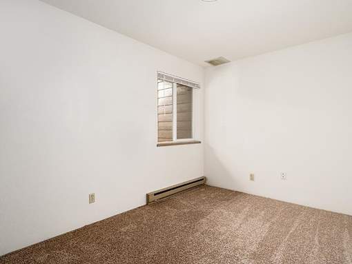 A room with a window and carpeted floor.