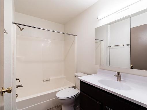 A white bathroom with a toilet, sink, and bathtub.