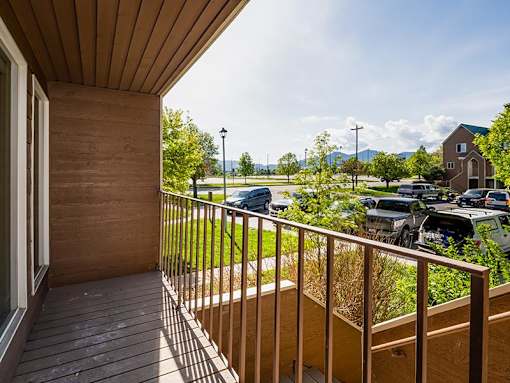 A balcony with a view of a parking lot and houses.
