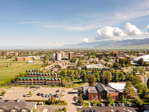 A large building with a green roof is surrounded by a parking lot.