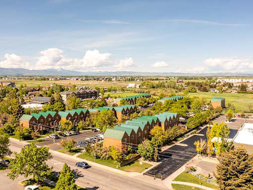 A large building complex with green roofs and a parking lot in front.