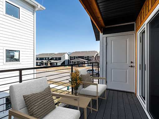 A balcony with a chair and a table with a plant on it.