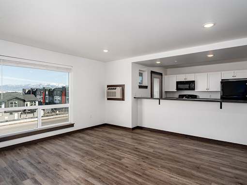 A room with wooden floors and a large window overlooking a street.