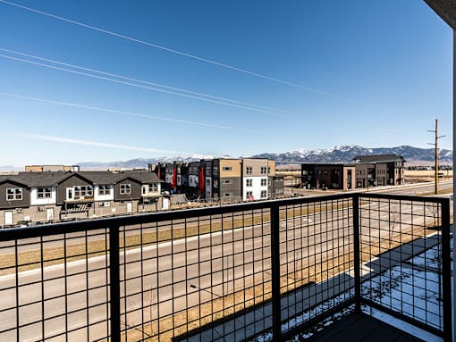 A balcony overlooks a residential area with houses and distant mountains.