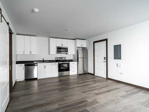 A kitchen with white cabinets and a black countertop.