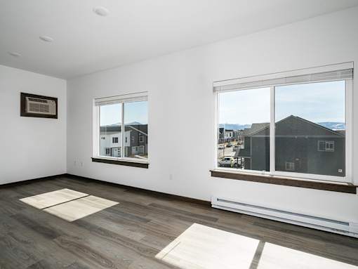 A room with two windows and a picture on the wall.