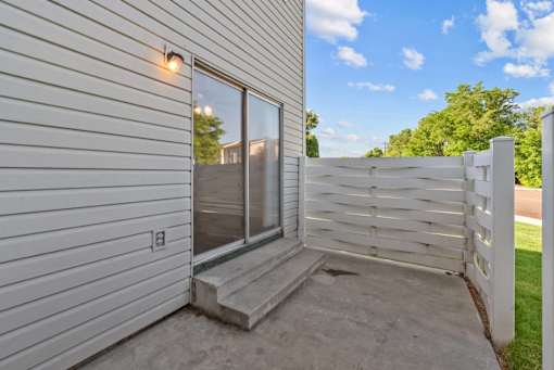 A white house with a sliding glass door and a white fence.