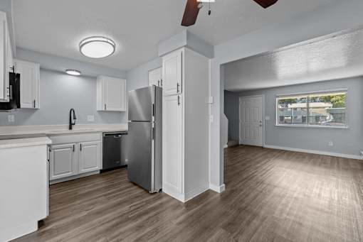 A kitchen with white cabinets and a refrigerator.