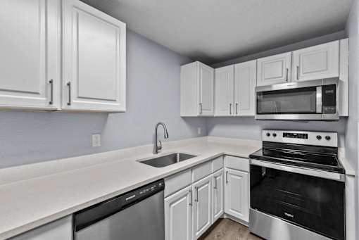 A kitchen with white cabinets and appliances.