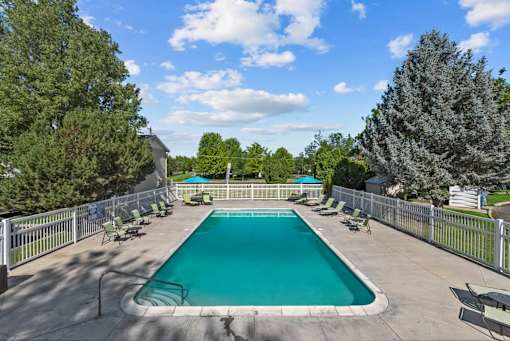 A large outdoor swimming pool surrounded by a fence and trees.