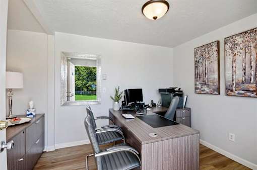 A home office with a desk, chairs, and a window.