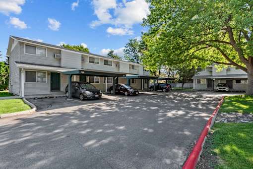 A sunny day at a residential complex with cars parked in the driveway.