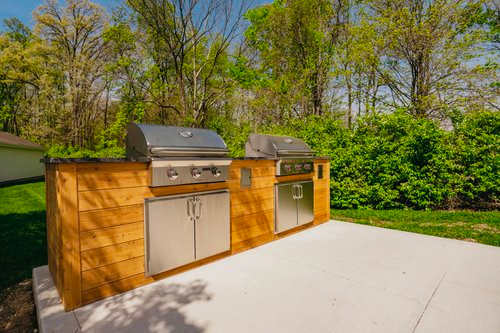 A wooden outdoor kitchen with a grill and sink.