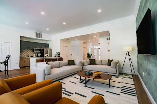A modern living room with a white couch, orange chairs, and a fireplace.
