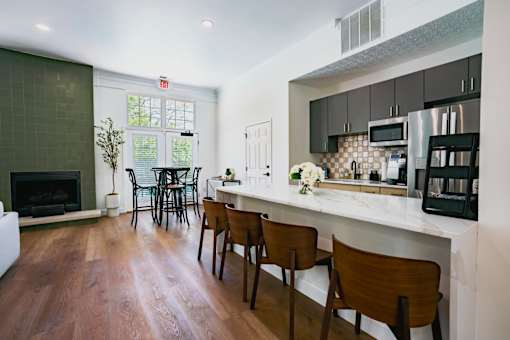 A kitchen with a white counter top and wooden chairs.