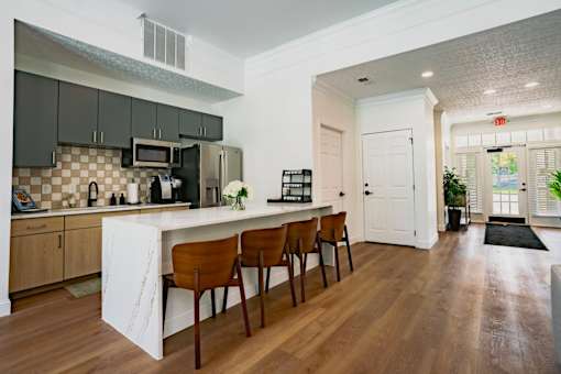 A kitchen with a white counter top and brown chairs.