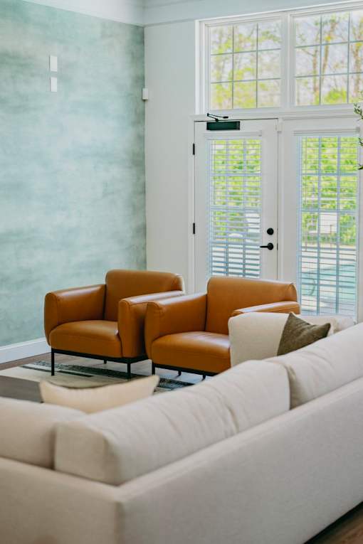 A living room with a white couch and two brown chairs.