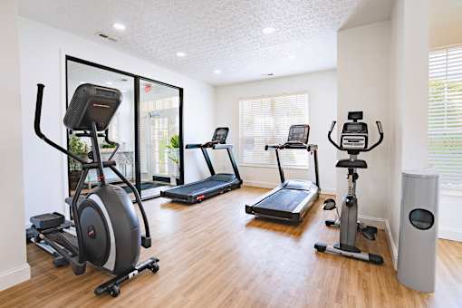 A room with a treadmill, elliptical trainer, and other exercise equipment.