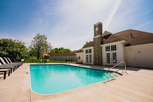 A large swimming pool in front of a house with a stone tower.