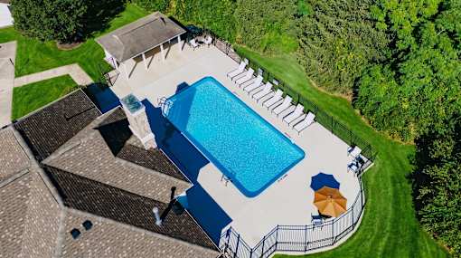 A large swimming pool surrounded by a fence and a small building.