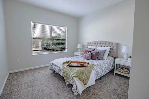 A bedroom with a large bed and a window with blinds.