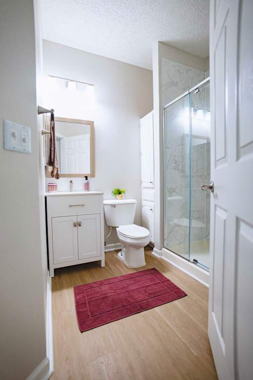 A white bathroom with a toilet, sink, and shower.