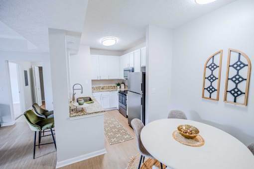 A kitchen with a table and chairs in the foreground and a refrigerator in the background.