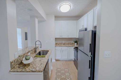 A kitchen with granite countertops and white cabinets.
