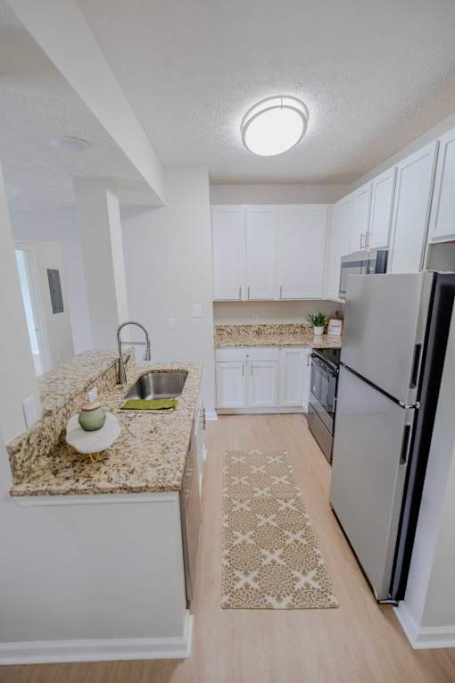 A kitchen with a granite countertop and a refrigerator.