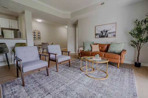 A living room with a grey rug and a gold coffee table.
