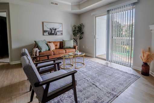 A living room with a brown couch, a grey armchair, and a grey rug.