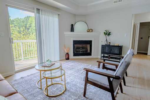 A living room with a fireplace, a glass table, and a chair.
