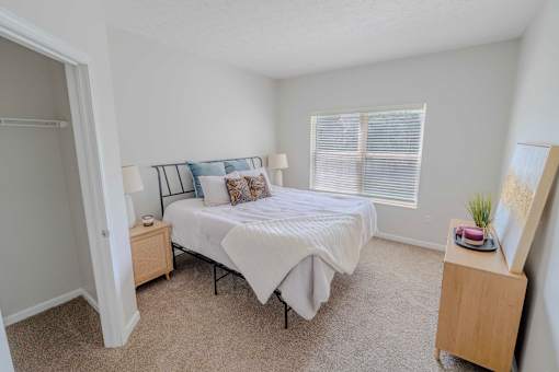 A bedroom with a bed, nightstand, and a small wooden cabinet.